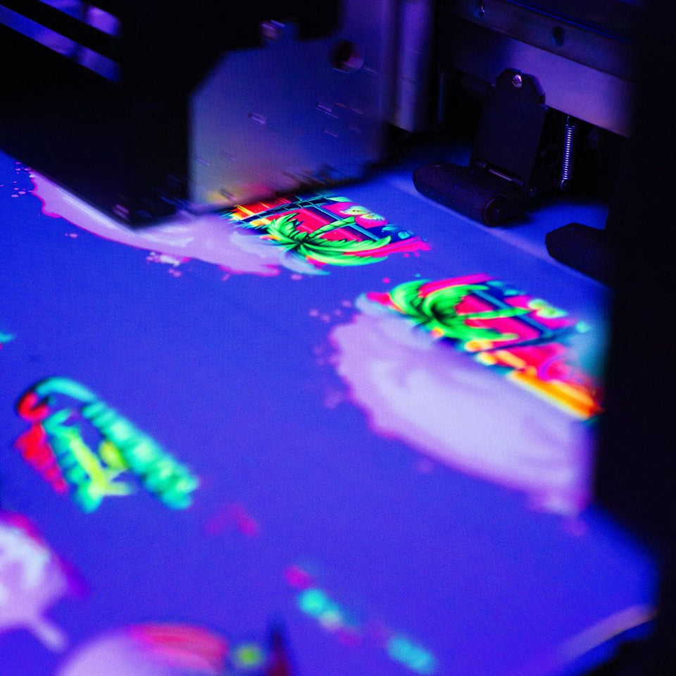 A close-up of colorful fluorescent direct to film (DTF) transfers on a surface, likely in the process of being printed or displayed.