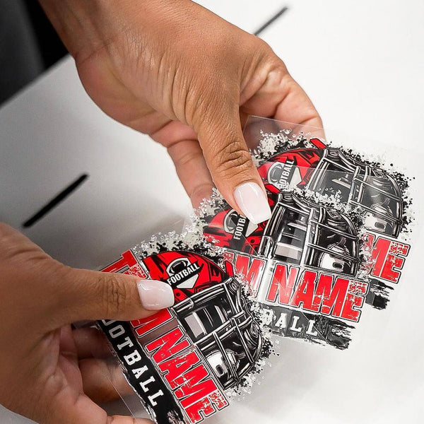 Hands holding custom UV DTF stickers for football, showcasing vibrant designs and personalized team names.