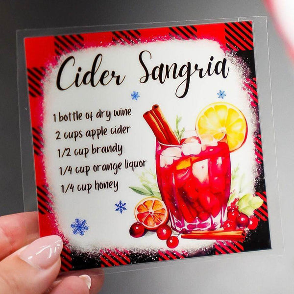 Hands holding UV DTF stickers for a festive drink recipe, showcasing vibrant colors and design details.