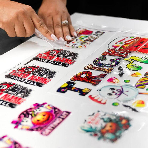 A person peeling UV DTF stickers from a sheet, showcasing vibrant designs for customizing tumblers.