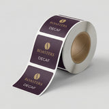 Roll of 'Roasters Decaf' labels on a light gray background