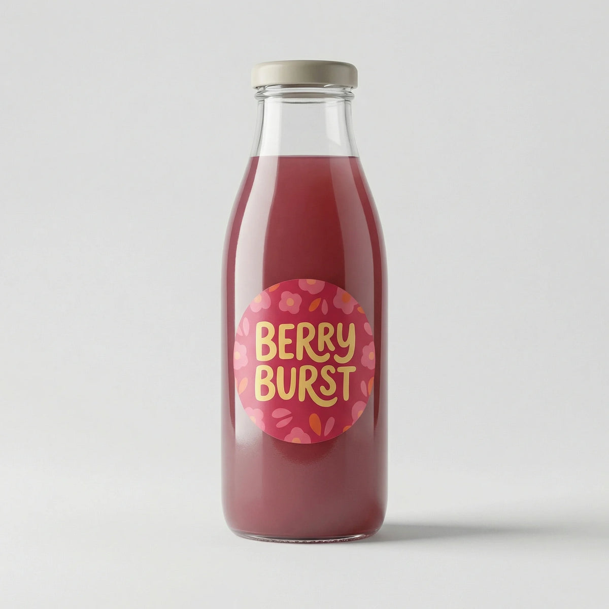Glass bottle of 'Berry Burst' juice with a pink label on a white background