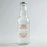 Clear glass bottle of 'Alchemy Spirit Mixers' on a light gray background