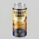 Can of Desert Oasis Lager with sand dunes, palm trees, and camels on the label against a gray background.